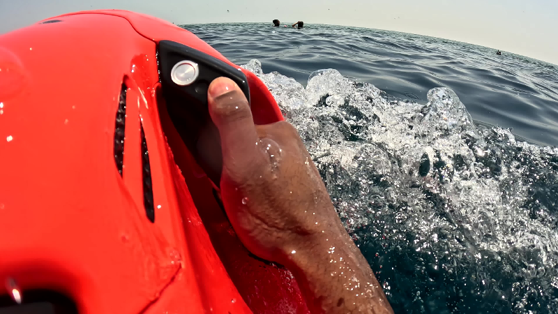 Point-of-view shot of a swimmer holding a motorised sea scooter at the ocean surface near a boat