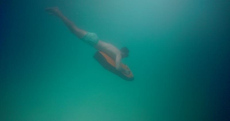 A swimmer holds on to a motorised sea scooter while swimming underwater