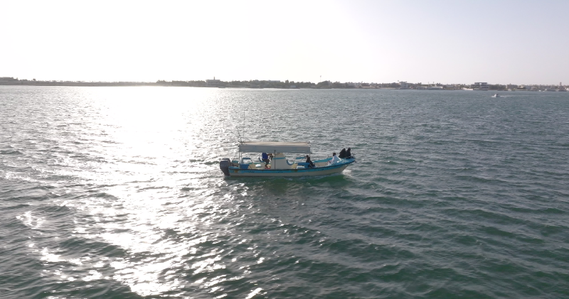 Aerial view of a small motorboat cruising across calm coastal waters